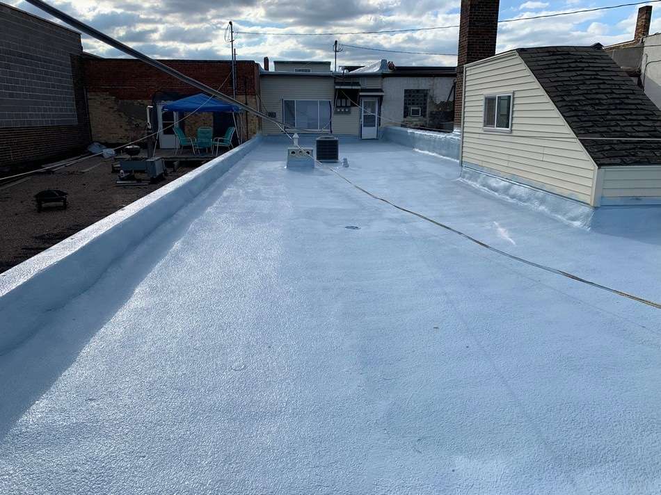 Spray foam roofing installation in progress showing seamless waterproof barrier application by certified professionals