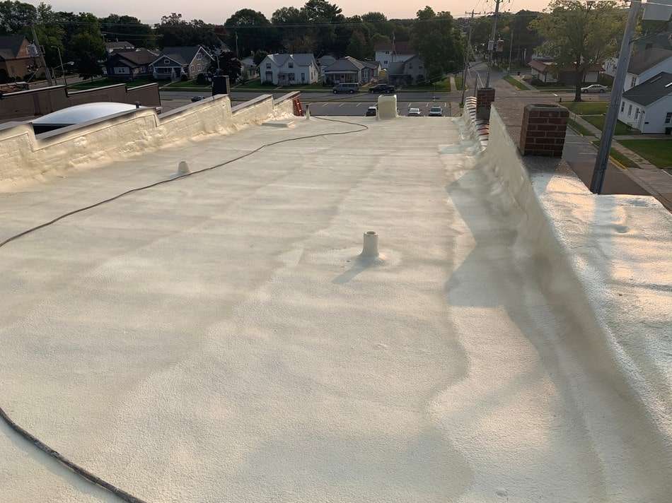 Spray foam roofing work by certified professionals demonstrating superior adhesion and weather protection properties